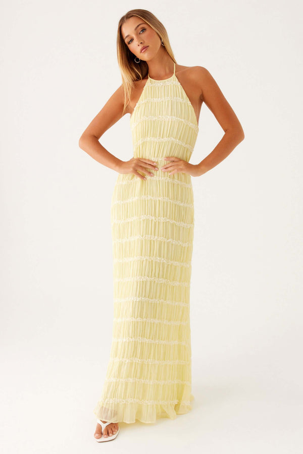 Woman wearing a yellow halter neck dress on a white background
