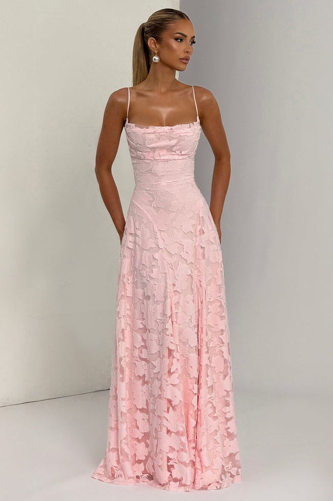 Woman wearing a pink lace dress against a plain background