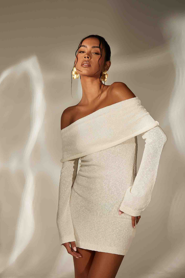 Woman wearing a stylish off-shoulder dress with a neutral background