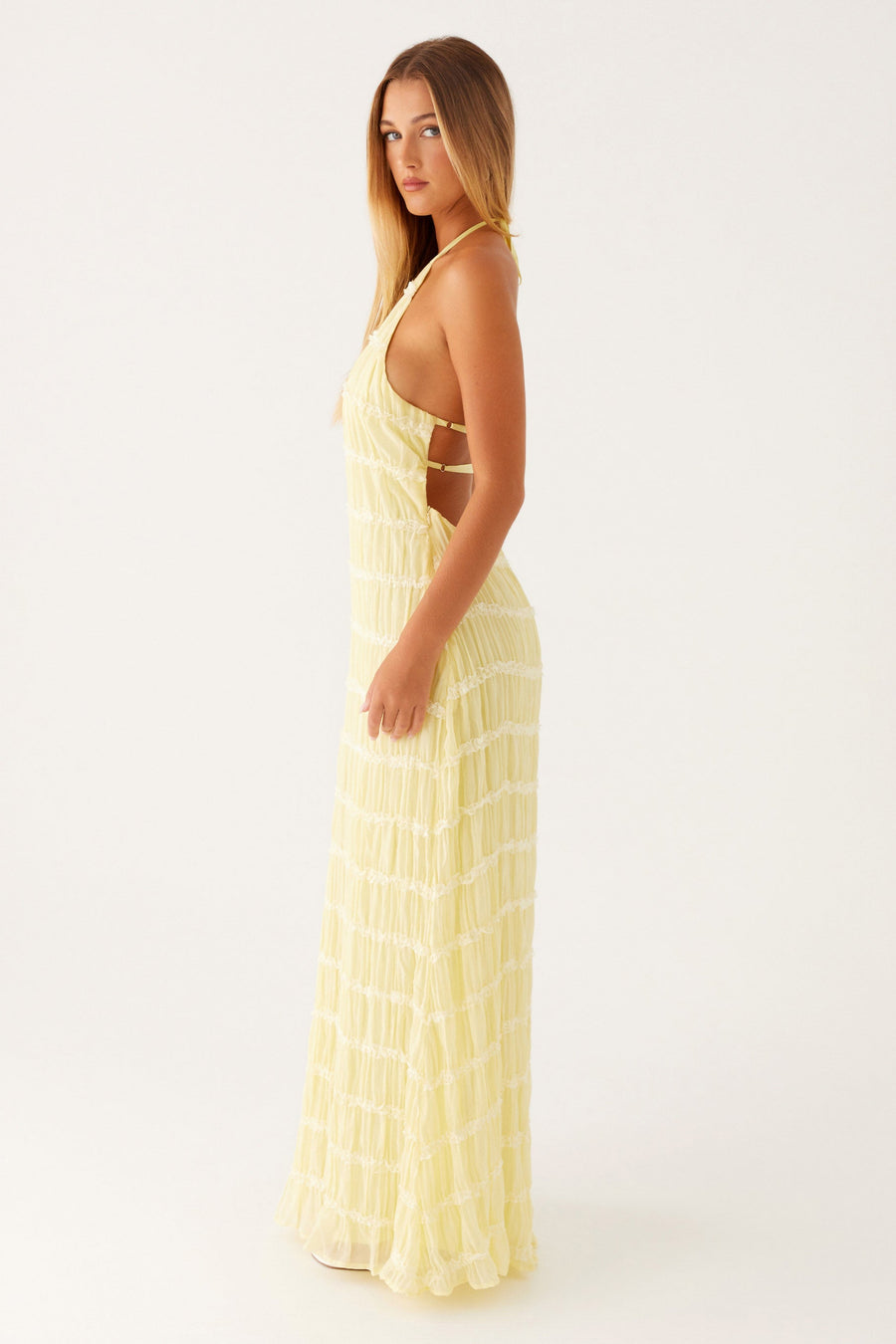 Woman wearing a yellow dress with cut-out design on a white background