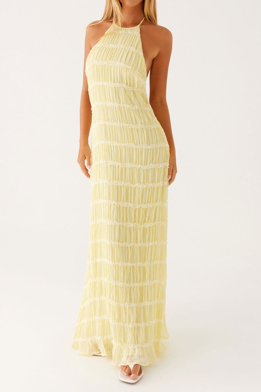 Woman wearing a yellow halter neck dress on a white background