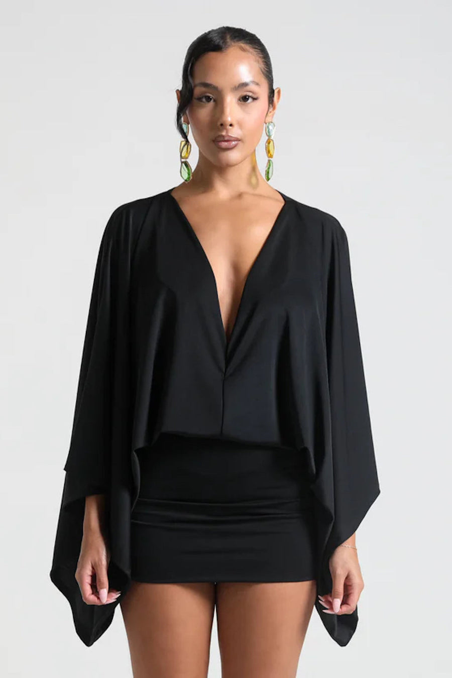 Woman wearing a black outfit with a cape on a white background