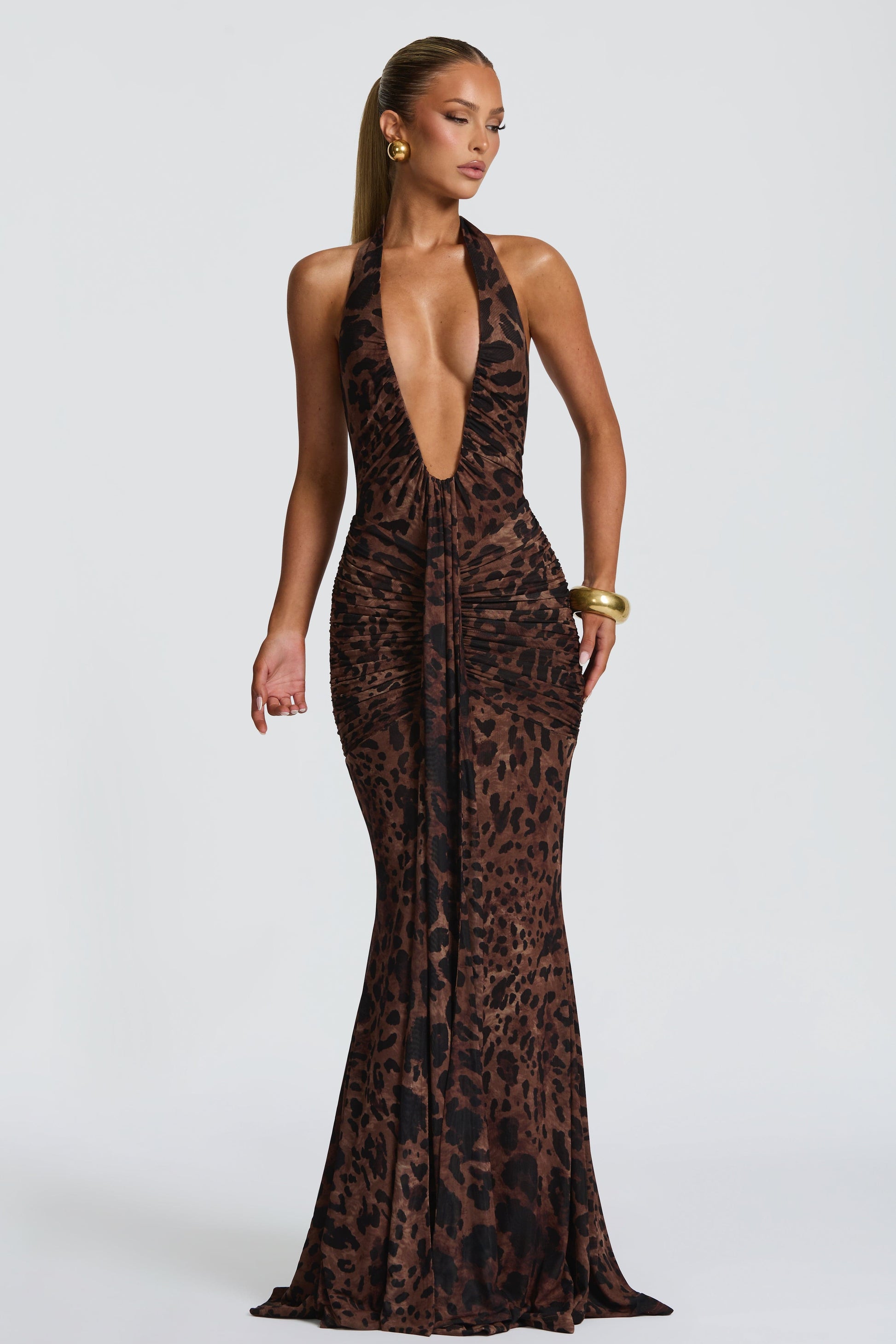 Woman wearing a leopard print halter neck gown on a white background