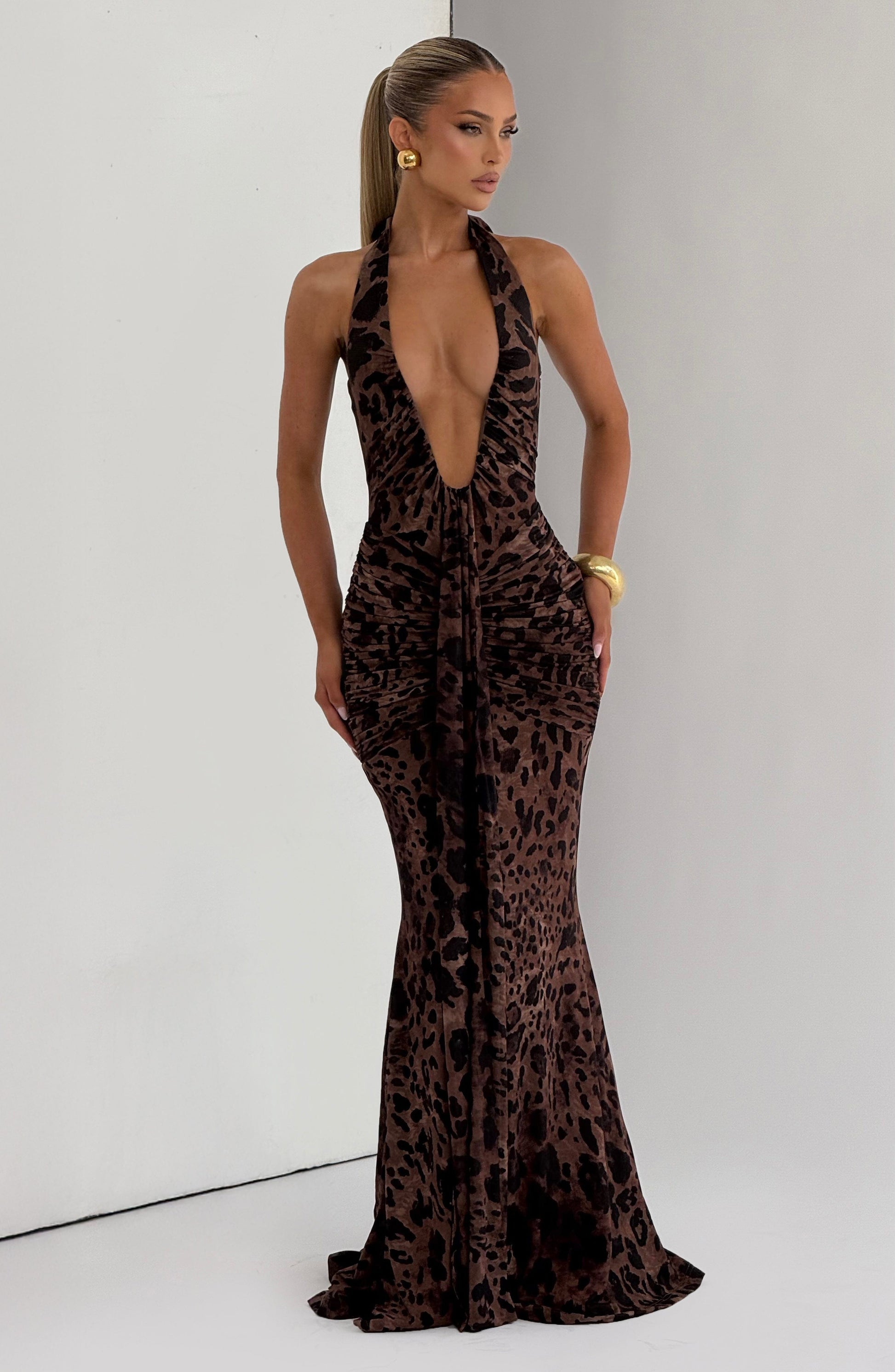 Woman wearing a leopard print halter neck gown on a plain background